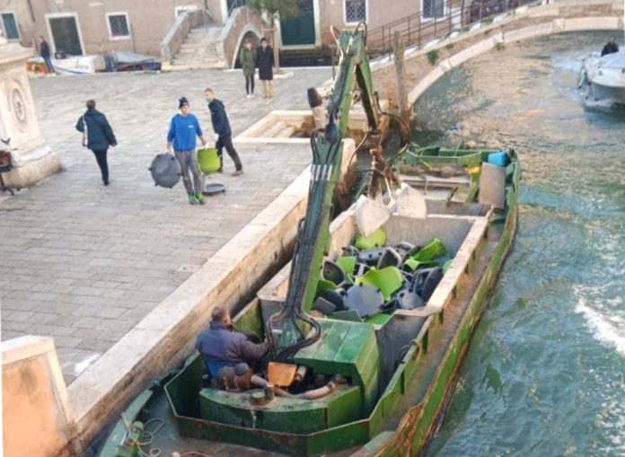 I famosi banchi a rotelle per le classi delle scuole mentre vengono rottamati a Venezia per mezzo di una chiatta