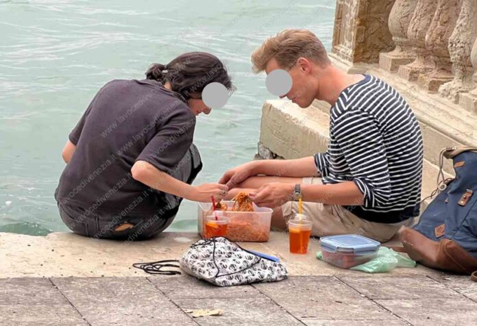 Ristorante Venezia, giovani mangiano seduti per terra vista laguna