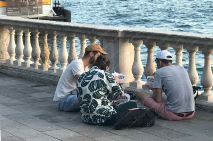 Turisti mangiano seduti per terra a Venezia, zona Biennale